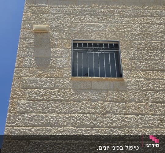 קיר אבן עם חלון סורג בשמש